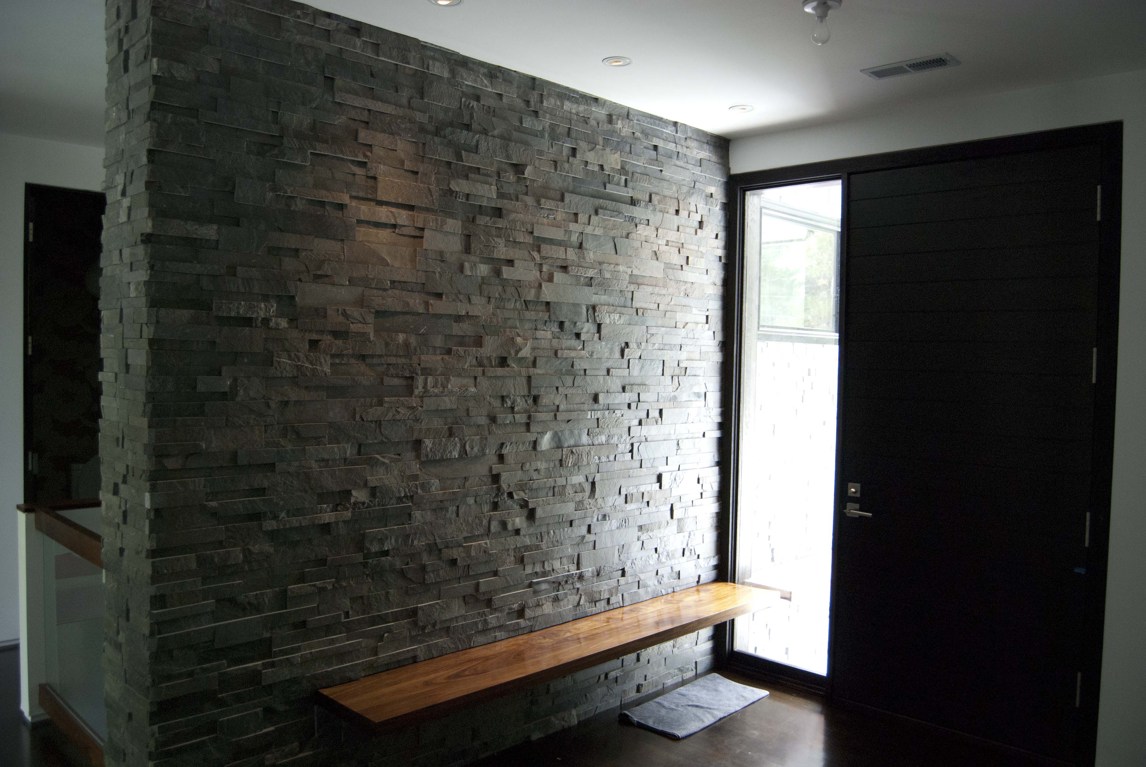 Charcoal Colored Stone Accent Wall in entryway of home with floating bench